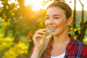 a young woman inserting an Invisalign aligner